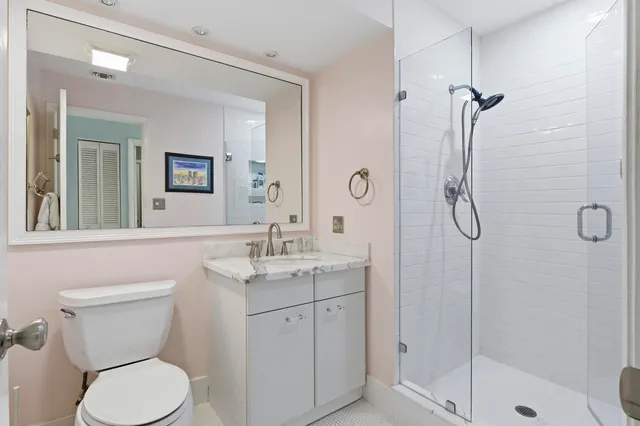 a bathroom with a toilet sink vanity granite and shower