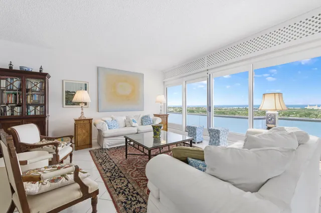 a living room with furniture floor to ceiling window and a table