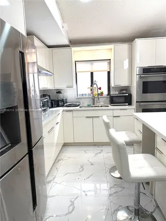 a kitchen with stainless steel appliances granite countertop a sink a stove a microwave a refrigerator and cabinets