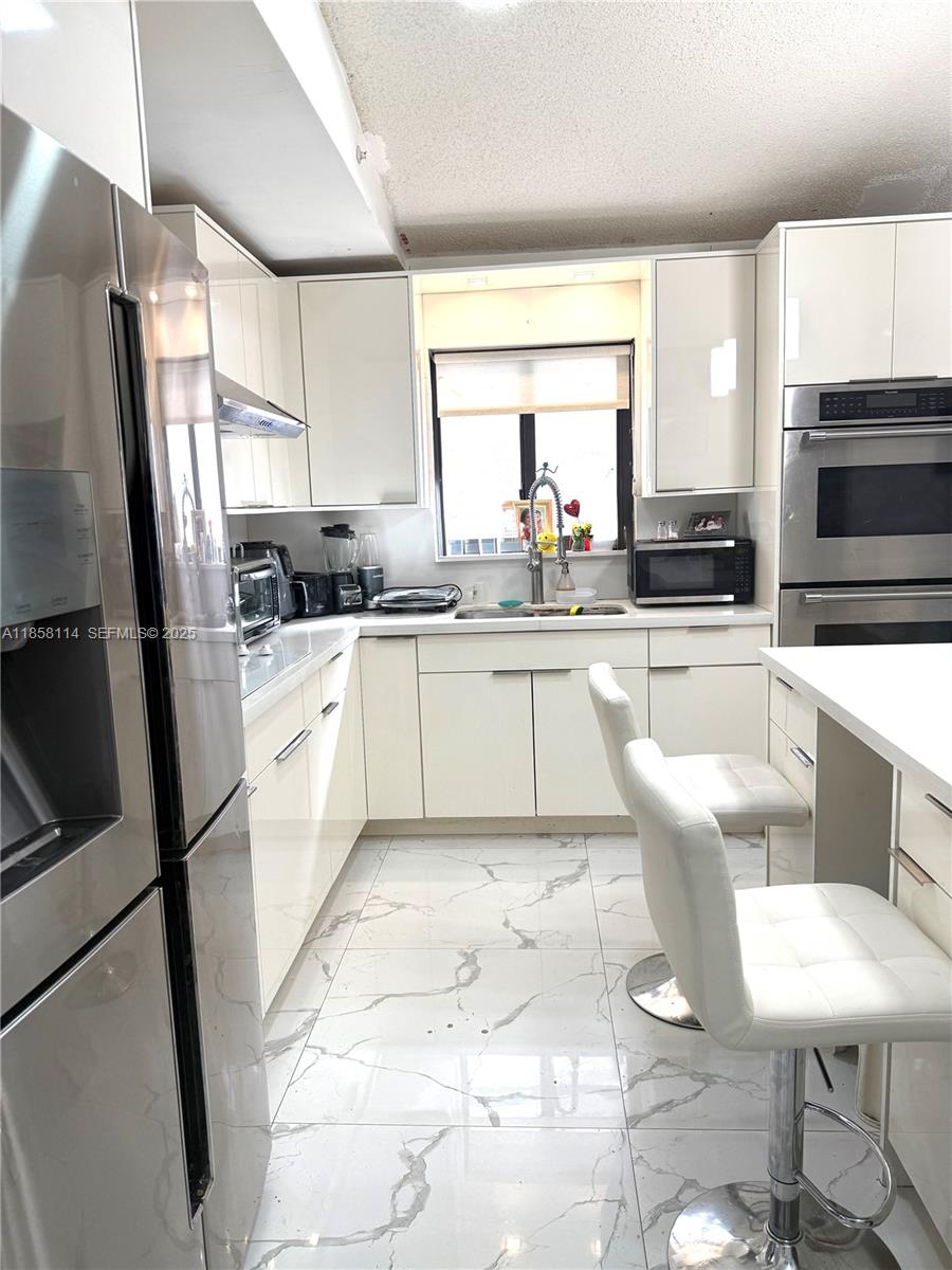 11266 Southwest 33rd Street Miami, FL 33165 - Photo 13 of 19 a kitchen with stainless steel appliances granite countertop a sink a stove a microwave a refrigerator and cabinets