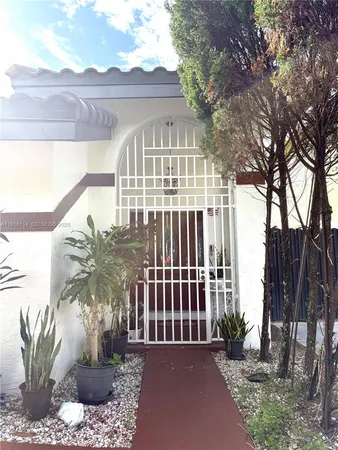 a view of a white house with a small yard and plants