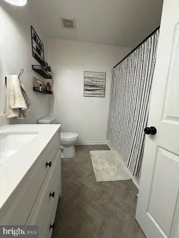 a bedroom with a bed and dresser with wooden floor