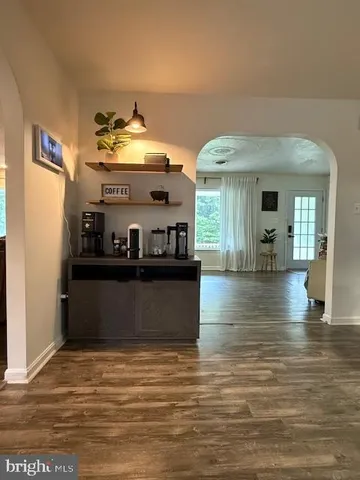 a view of a living room with kitchen island stainless steel appliances wooden floor and living room view