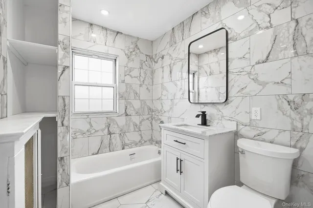 a bathroom with a toilet sink vanity tub and mirror