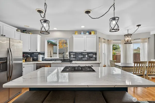 a kitchen with kitchen island granite countertop a stove a sink a refrigerator wooden floor cabinets and dining table
