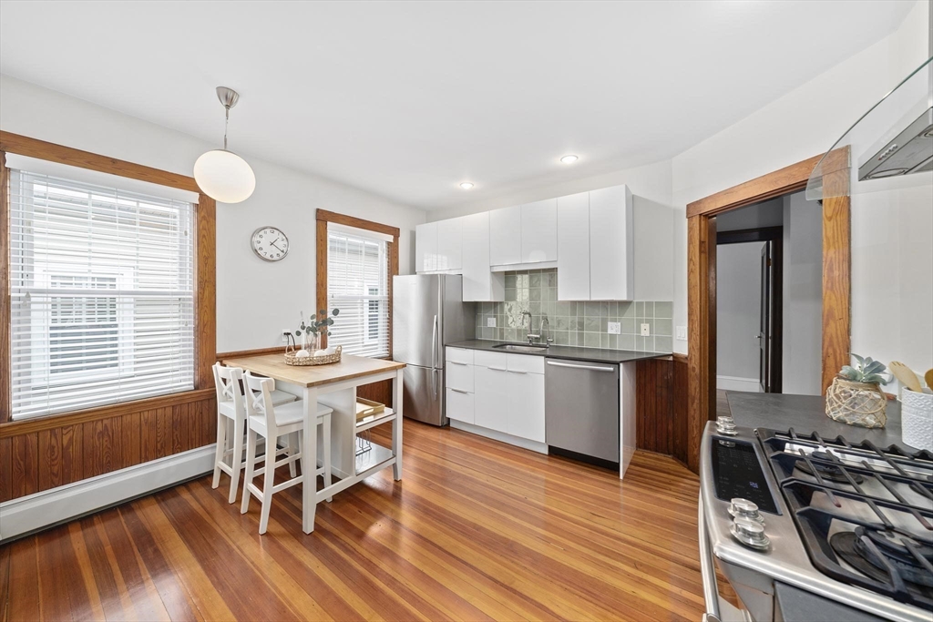 75 Parkton Road, Unit 3 Boston, MA 02130 - Photo 11 of 40 a kitchen with stainless steel appliances granite countertop a stove top oven a sink dishwasher a dining table and chairs with wooden floor