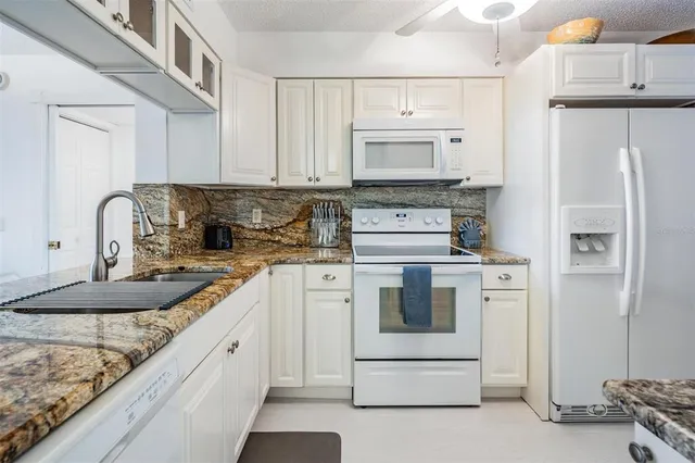 a kitchen with white cabinets and white appliances