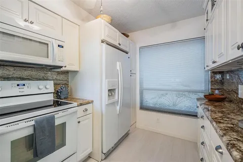 a kitchen with stainless steel appliances granite countertop a stove and a refrigerator with white cabinets