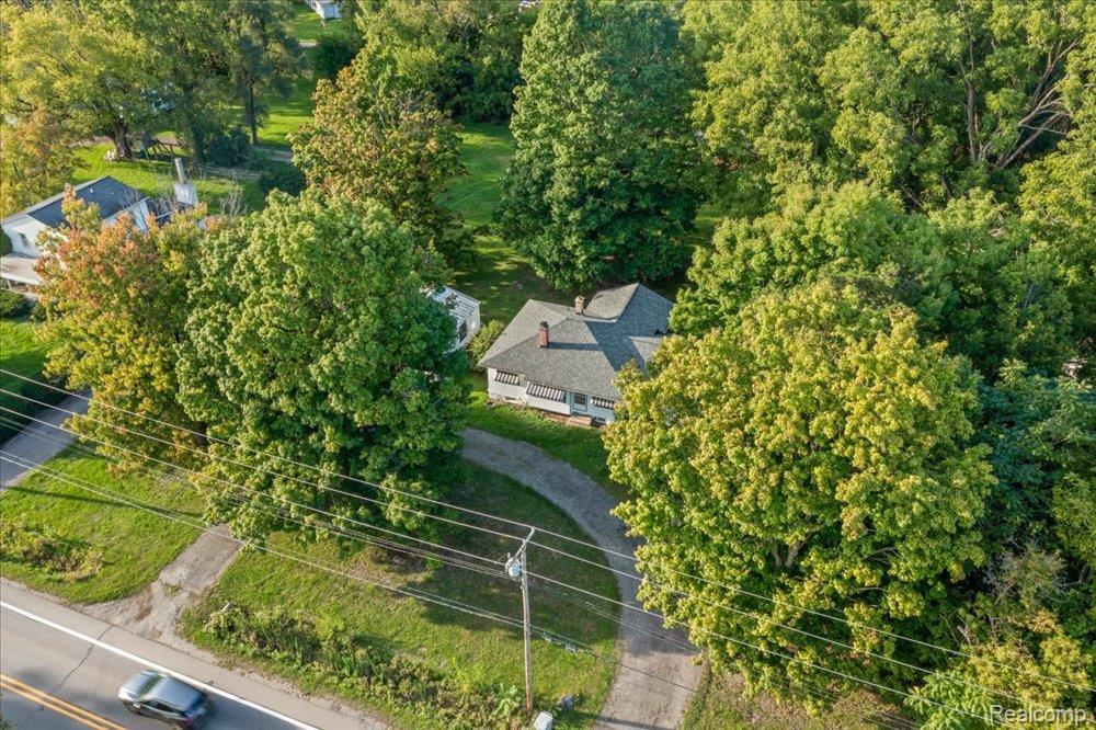 59380 10 Mile Road South Lyon, MI 48178 - Photo 1 of 53 Secluded property with a pitched shingle roof, surrounded by mature trees, featuring a curved asphalt driveway