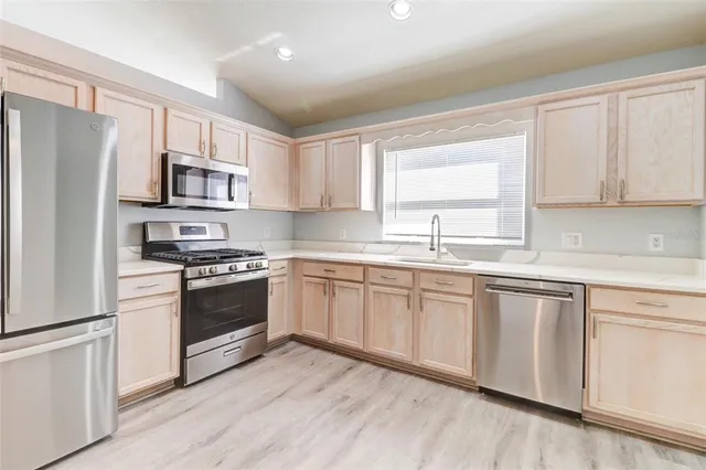 a kitchen with stainless steel appliances granite countertop a stove a sink and a refrigerator