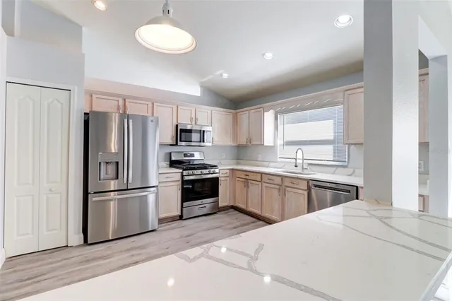 a kitchen with granite countertop a refrigerator stove top oven and sink