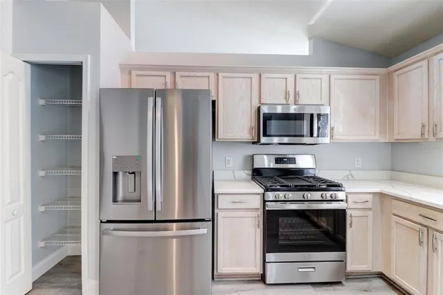 a kitchen with cabinets stainless steel appliances and a window