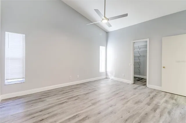 an empty room with wooden floor closet and windows