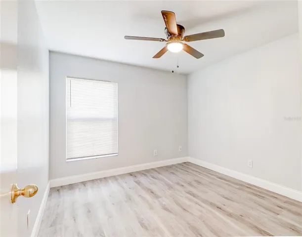 an empty room with a window and ceiling fan