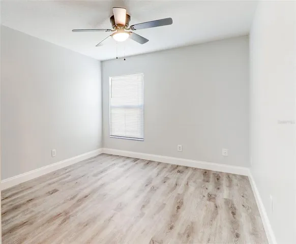 an empty room with a window and a fan