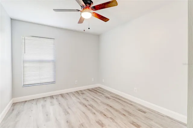 an empty room with a window and ceiling fan