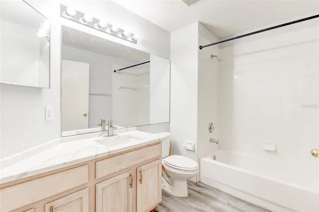 a bathroom with a granite countertop sink a toilet and shower