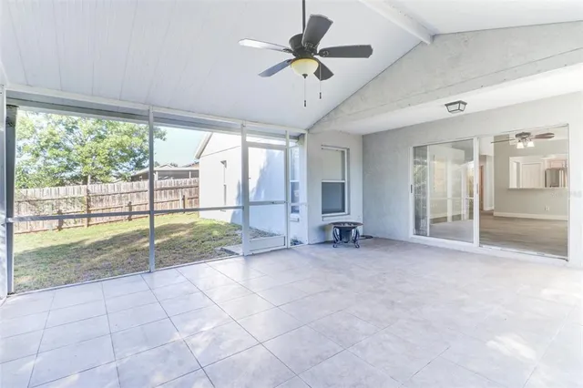 a view of an empty room with a ceiling fan and window