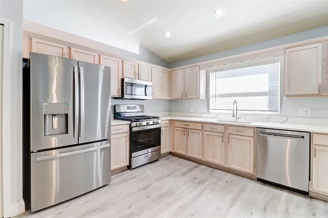 a kitchen with granite countertop a refrigerator stove and sink
