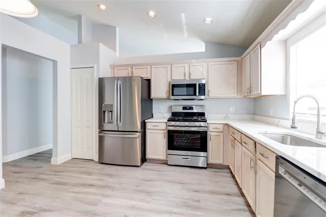 a kitchen with kitchen island wooden cabinets stainless steel appliances and window