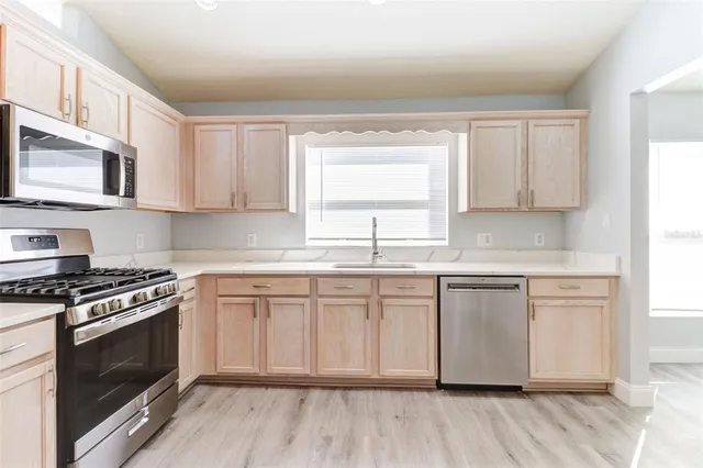 a kitchen with stainless steel appliances granite countertop a stove a sink and a microwave