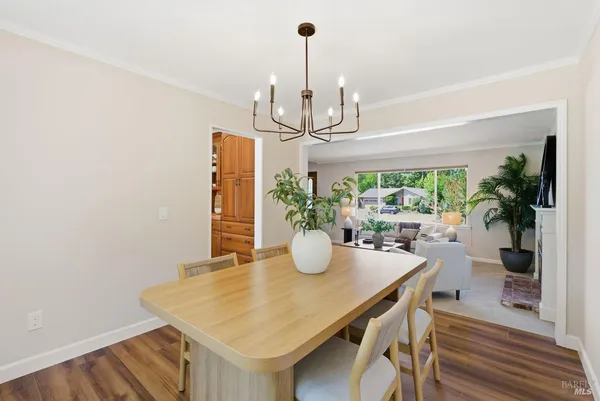 a kitchen with stainless steel appliances granite countertop a stove top oven a refrigerator a sink and a dining table with wooden floor