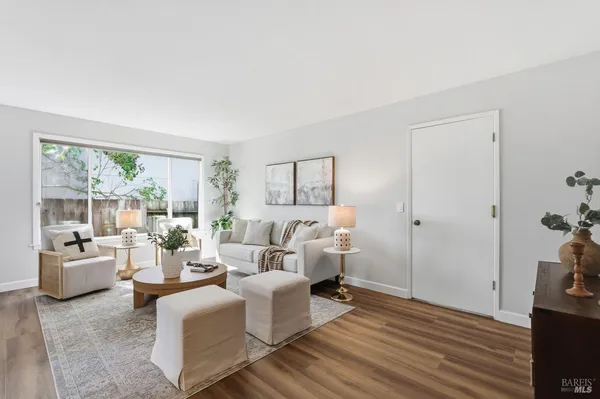 a living room with furniture large window and wooden floor