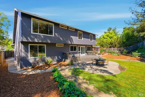 a backyard of a house with large tree and wooden fence
