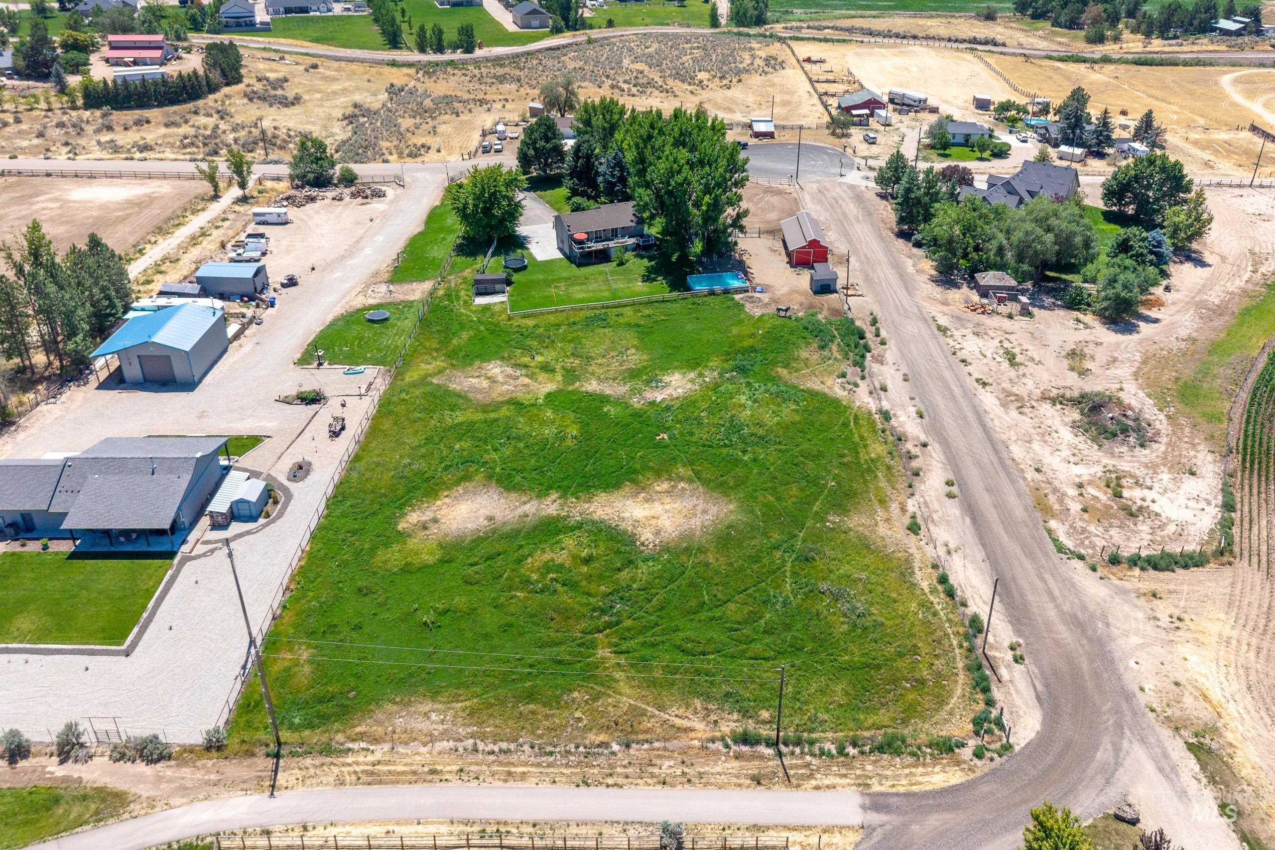9696 Gloria Road Middleton, ID 83644 - Photo 48 of 50 Expansive undeveloped land parcel featuring existing structures, a blue-roofed outbuilding, a red barn, and a residential dwelling with a pool