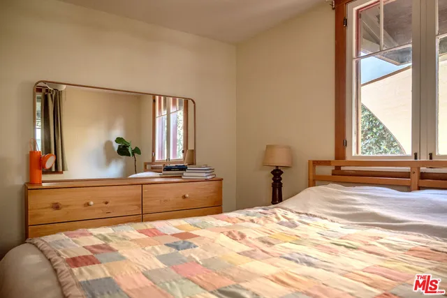 a bedroom with a large bed and a large mirror next to a window