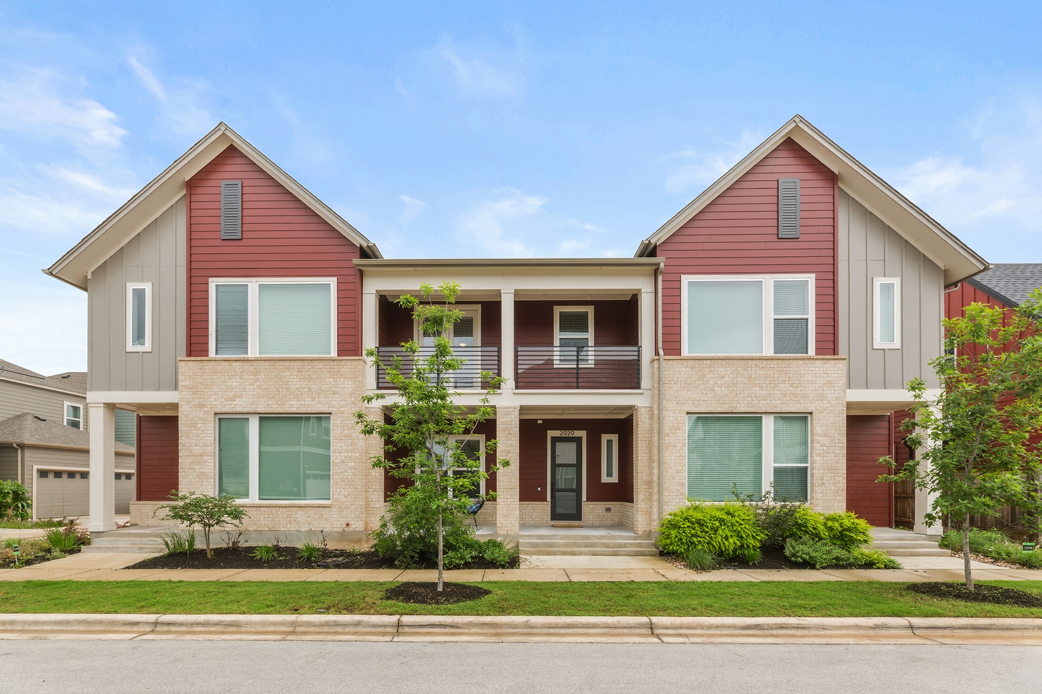 2929 Moreno Street Austin, TX 78723 - Photo 2 of 40 Modern townhome exterior featuring a combination of red siding, light gray vertical siding, and light-colored stucco