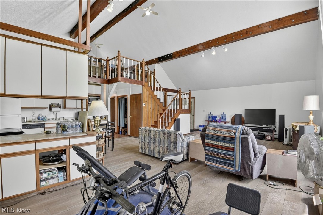 1526 Stevenson Road Ashtabula, OH 44004 - Photo 11 of 50 Open-concept living space featuring vaulted ceilings with exposed wood beams, a prominent wood staircase leading to a loft, and wood-finish flooring