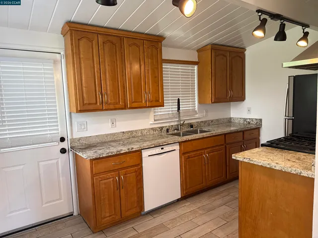 a kitchen with stainless steel appliances granite countertop wooden cabinets a sink and dishwasher