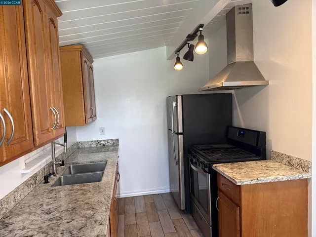 a kitchen with stainless steel appliances granite countertop a sink a stove and a refrigerator