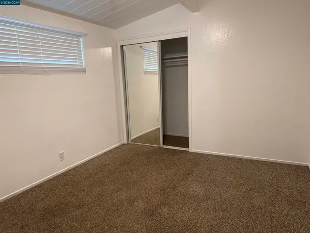 a view of an empty room with closet and a window