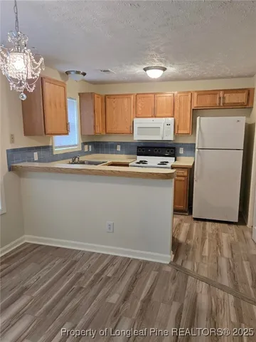 a kitchen with stainless steel appliances granite countertop a sink a stove a refrigerator with grey cabinets and wooden floor