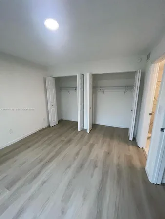 an empty room with wooden floor and window