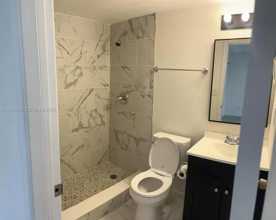 a bathroom with a granite countertop toilet and a shower