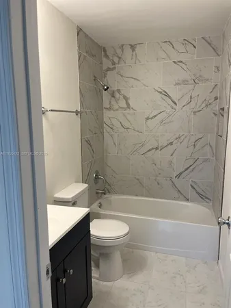 a bathroom with a granite countertop bathtub shower sink vanity and toilet