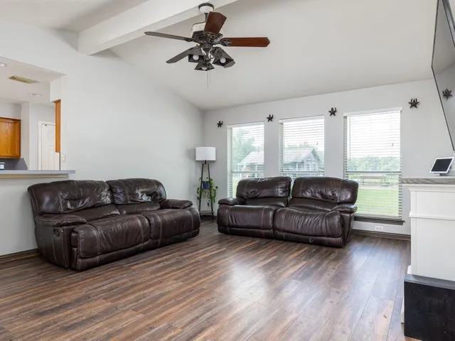 a living room with couches and a flat screen tv with wooden floor