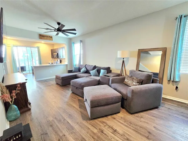 a living room with furniture ceiling fan and a wooden floor