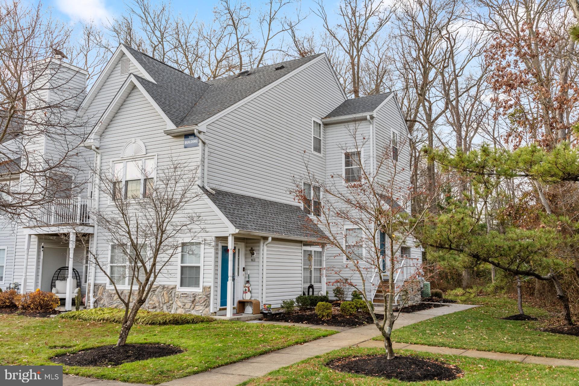 a front view of a house with a yard and large tree