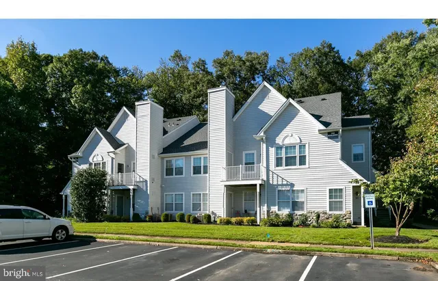 a view of a white house next to a yard with big trees