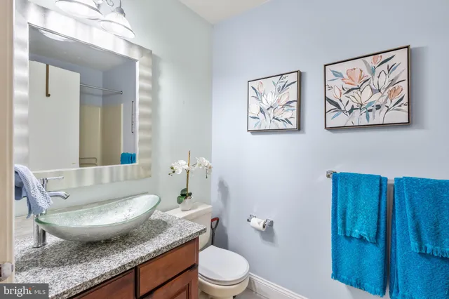 a view of a bathroom with a granite countertop toilet a sink and a mirror