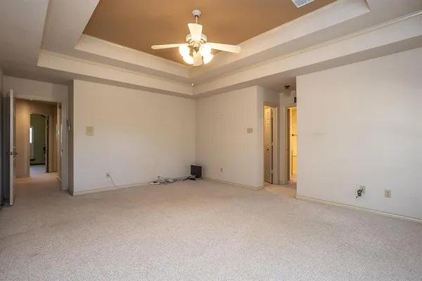 an empty room with a chandelier fan and a bathroom