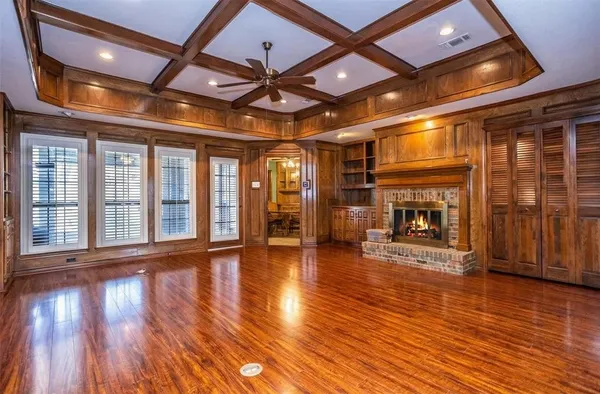 a view of an empty room with wooden floor and a fireplace