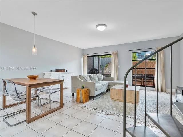 a living room with furniture a rug potted plant and windows