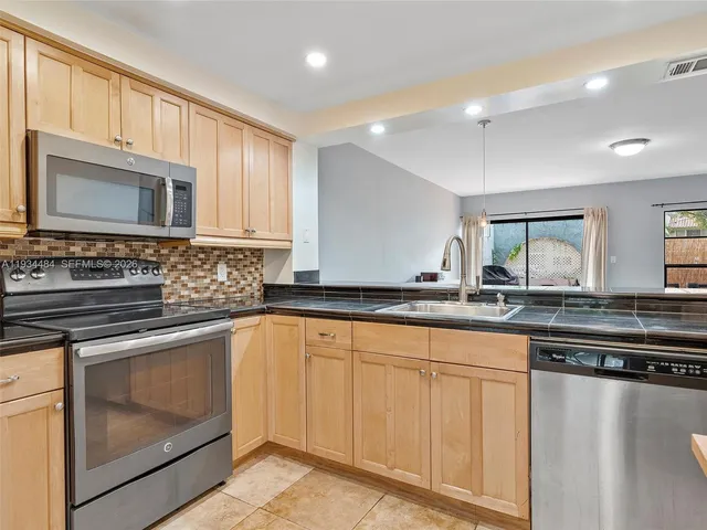 a kitchen with granite countertop a stove sink and microwave
