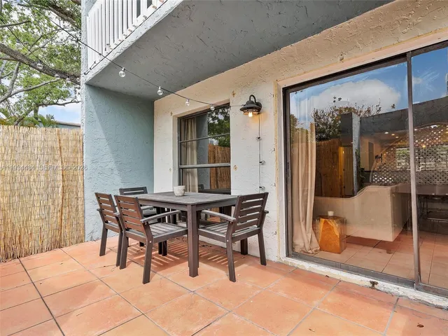 a patio with table and chairs and potted plants
