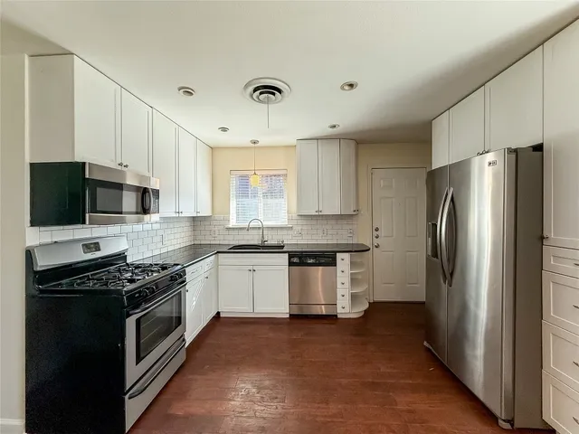 a kitchen with stainless steel appliances granite countertop a stove top oven a refrigerator and a sink